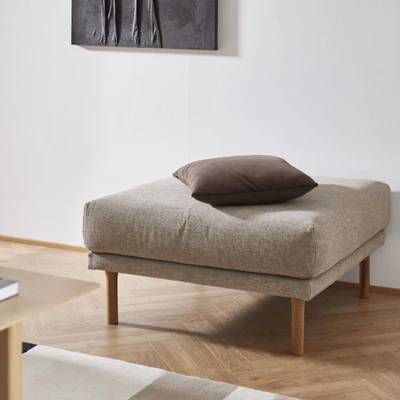 Puff i nyansen sand i Verdon-tyg stående på trägolv med en brun kudde ovanpå