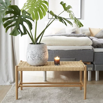 Bänk med träben och flätad sits framför säng