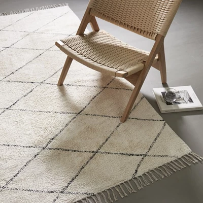 Fåtölj i franskt flätning stående på beige matta