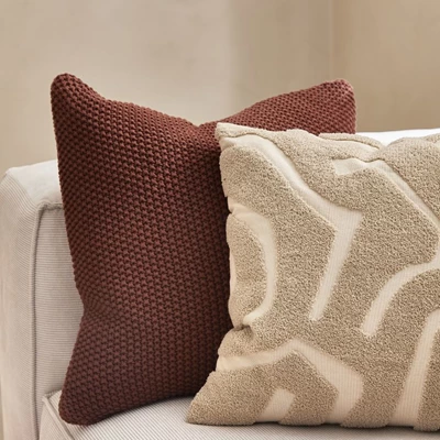 Två kuddar i respektive röd och beige nyans