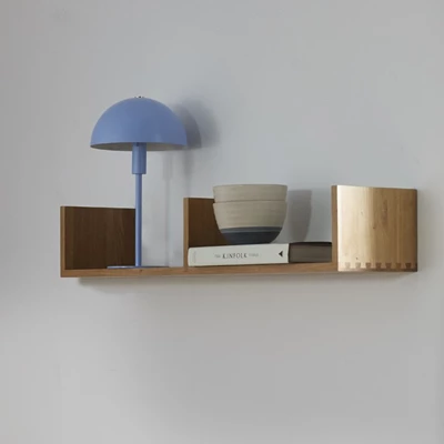 Blå bordslampa stående på vägghylla i trä