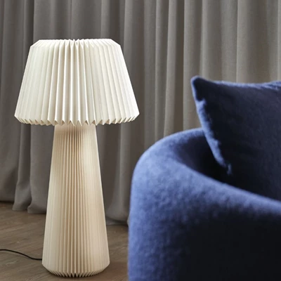 Golvlampa i papper stående vid blå soffa