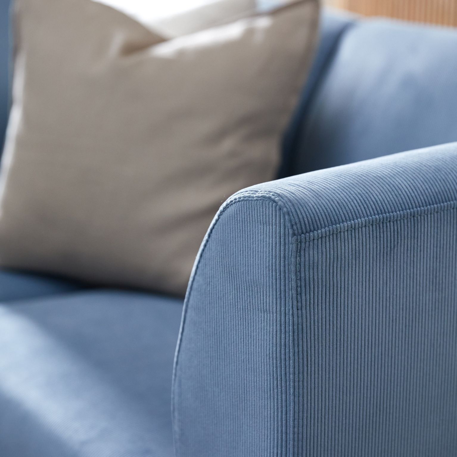 Närbild av armstöd på soffa i ljusblå sammet