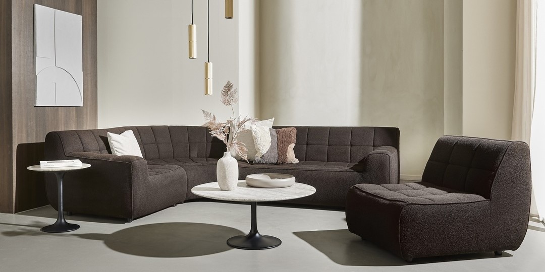 Mörk hörnsoffa med marmorbord och dekorativa kuddar