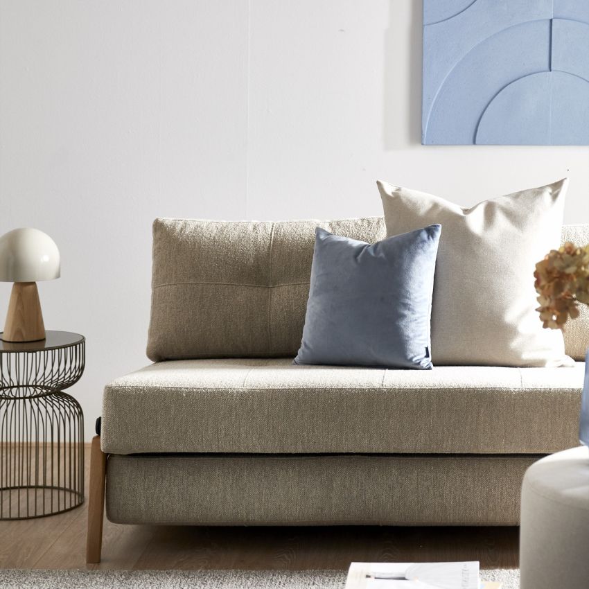 Lys stue med stilren sovesofa dekoreret med puder og minimalistisk indretning.