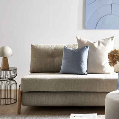 Lys stue med stilren sovesofa dekoreret med puder og minimalistisk indretning.