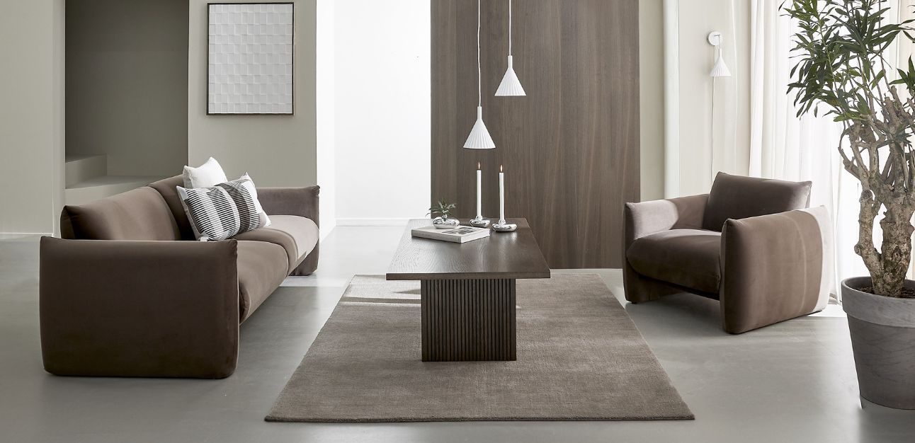 Brun soffa och fåtölj med soffbord och prydnader