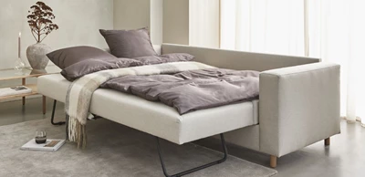 Uppfälld sovesofa med täcke och kuddar