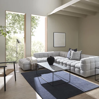 Vardagsrum med blått golv och en stor, grå U-soffa