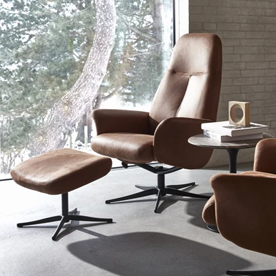 Fåtölj med pall i brunt läder.