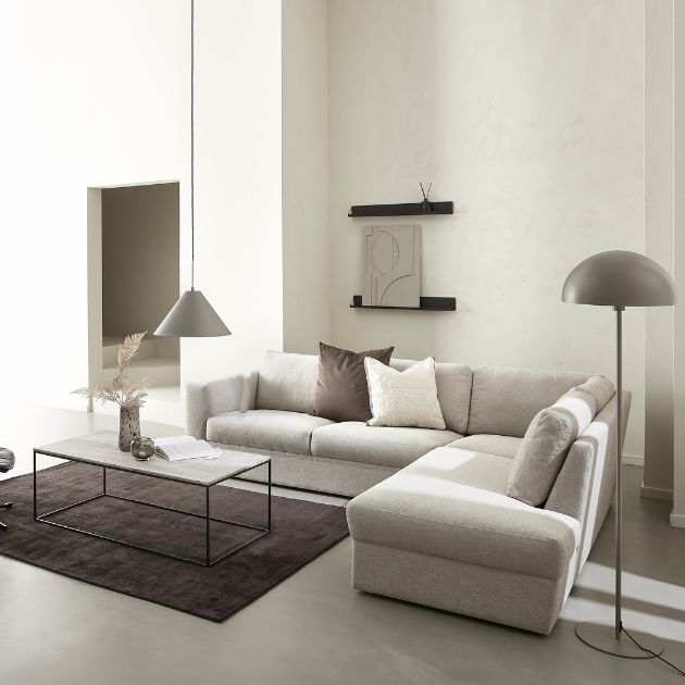 Vardagsrumsmiljö med hörnsoffa, matta, soffbord och dekorationer på väggarna