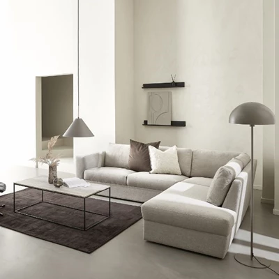 Vardagsrumsmiljö med hörnsoffa, matta, soffbord och dekorationer på väggarna