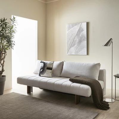 Design uden navn - 2024-08-19T102405.461.jpg Vit bäddsoffa med kanalsömmar stående mot en vägg med en målning i vita nyanser hängande ovanför