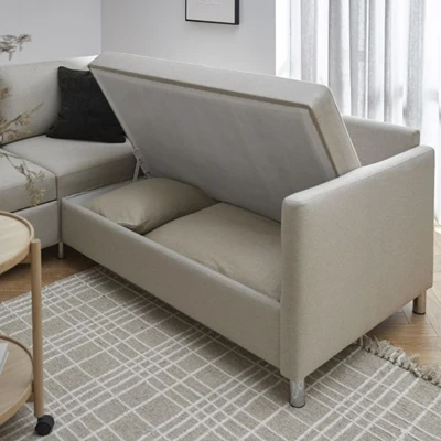 Titta in i förvaringsfacket på hörnbäddsoffa i grå textil