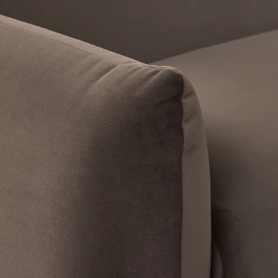 Detaljerad närbild av en brun tygsoffas armstöd, som framhäver den mjuka och lyxiga texturen.