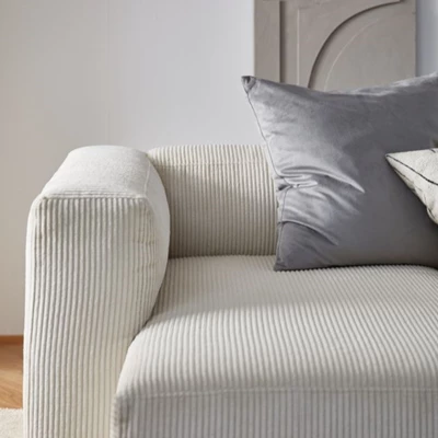 Vit soffa med räfflad design, med en blå kudde på soffan