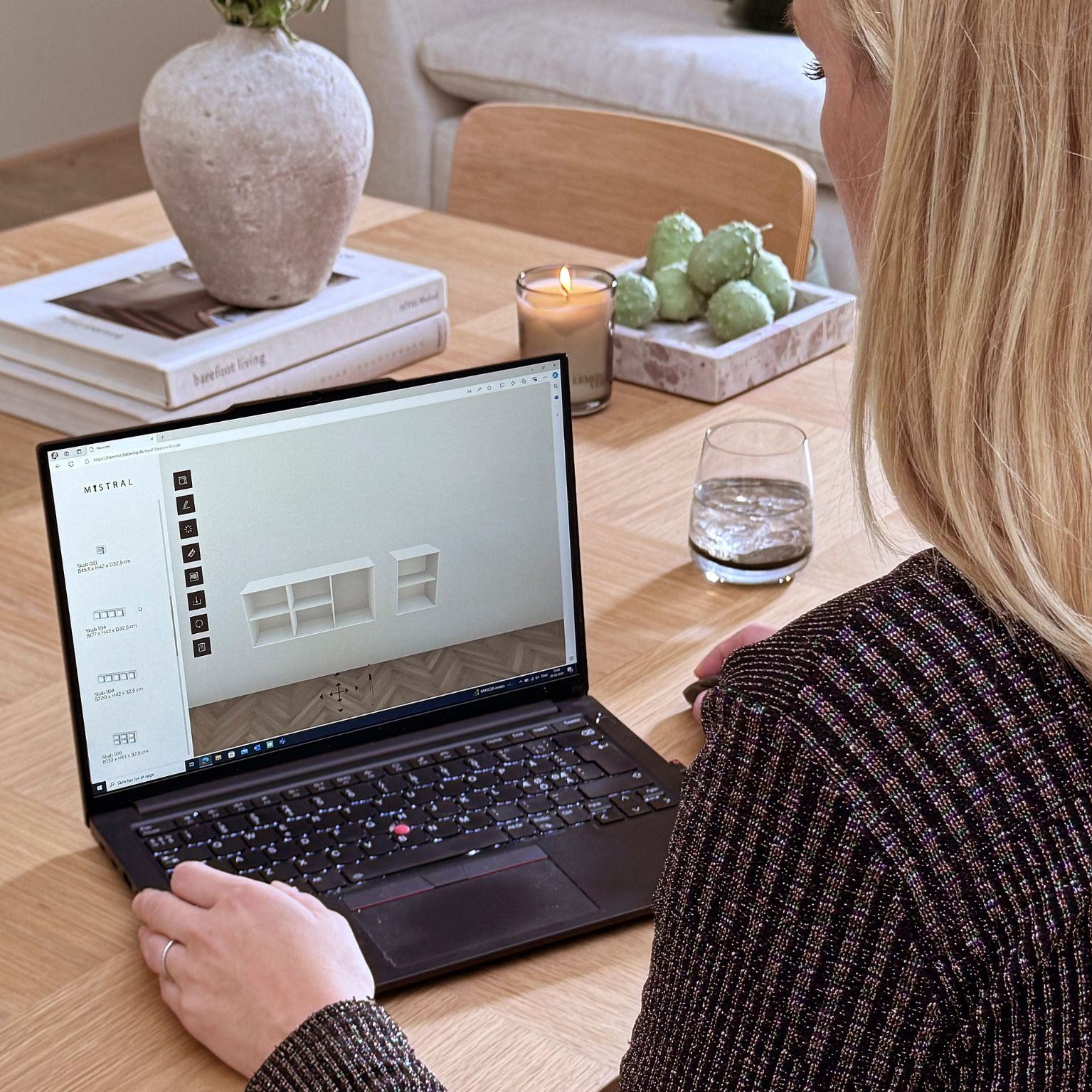 Kvinna som sitter framför en bärbar dator och håller på att designa en hylla i Mistrals ritverktyg.