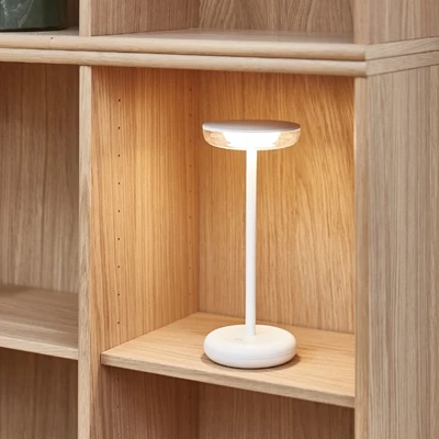 Närbild av en bordslampa som är placerad i en kubhylla i ljus ek