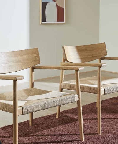 Två ljusa trästolar med flätad sits placerade på en röd matta i ett minimalistiskt matrum