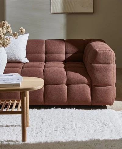 Modern brun soffa med en mjuk, stoppad yta, placerad på en ljus matta vid ett soffbord i trä