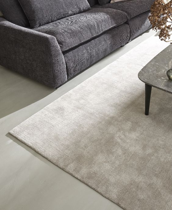 Ljus matta under en mörkgrå soffa med ett soffbord i hörnet, vilket skapar en mysig atmosfär
