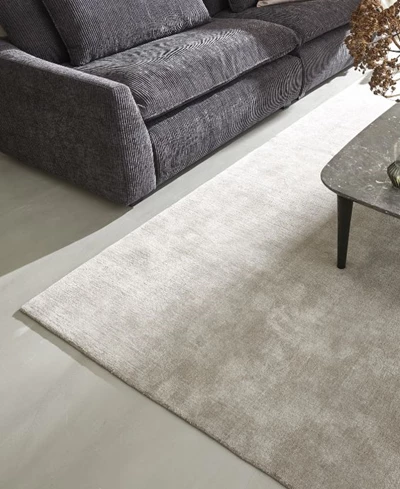 Ljus matta under en mörkgrå soffa med ett soffbord i hörnet, vilket skapar en mysig atmosfär