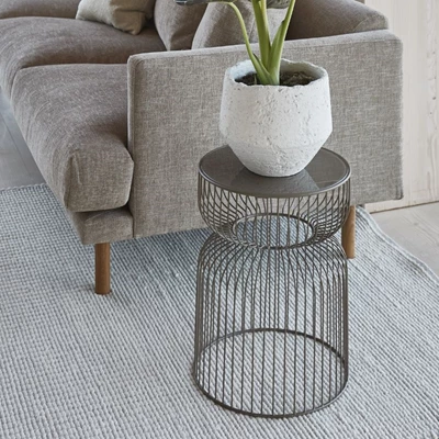 Sidobord i tråddesign med en vas stående ovanpå