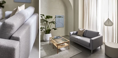 Tvåsitsig grå soffa på betonggolv med ett soffbord i trästomme och glasskiva