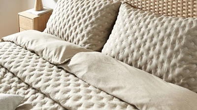 Säng med flätad sänggavel och beige sängkläder