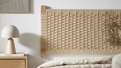 Trägavel och nattduksbord bredvid säng med beige filt