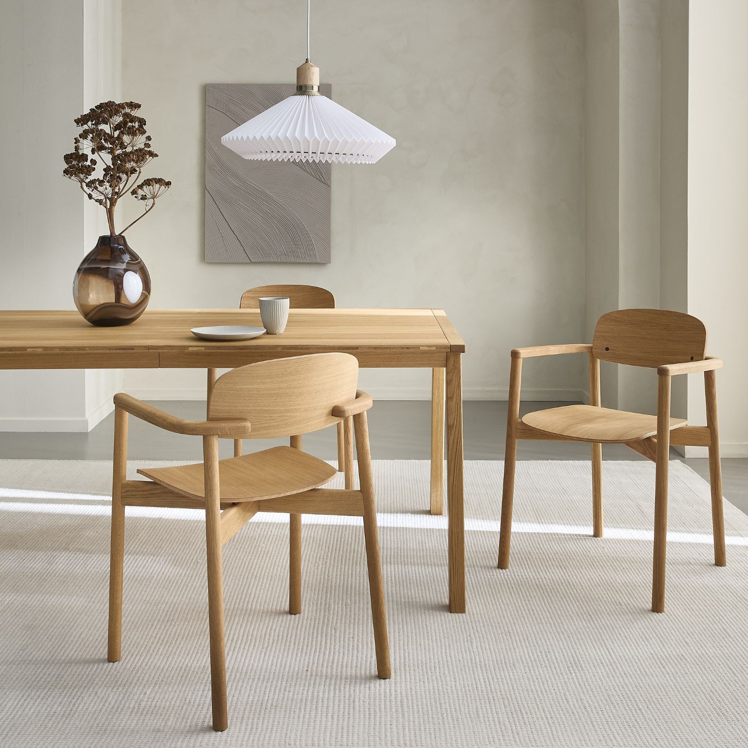 Ljust trä matbord med matchande stolar, minimalistisk inredning och vas i glas som dekoration