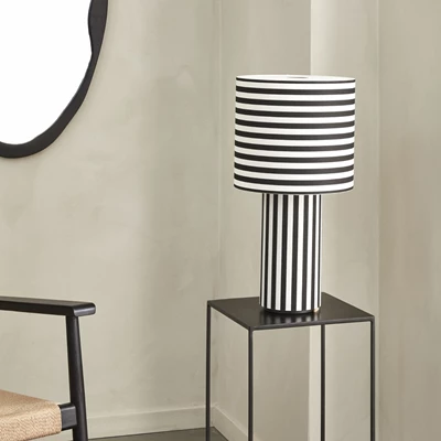 Bordlampa med svarta och vita ränder stående på sidobord.