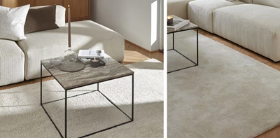 Ljus vardagsrum med vit soffa och minimalistiskt soffbord med bordsskiva i travertin.