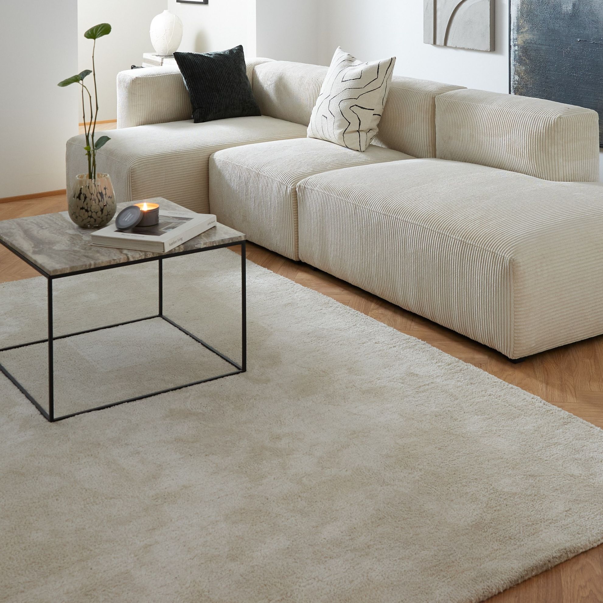 Ljus vardagsrum med vit soffa och minimalistiskt soffbord med bordsskiva i travertin.