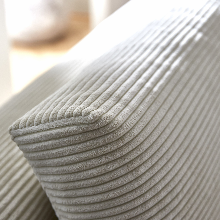 Närbild på bäddsoffa med sammetsoverdrag i ljusgrått, där en läderrem syns på den nedre delen av soffaens bas