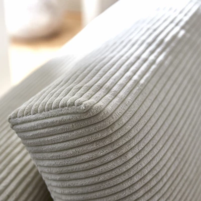 Närbild på bäddsoffa med sammetsoverdrag i ljusgrått, där en läderrem syns på den nedre delen av soffaens bas