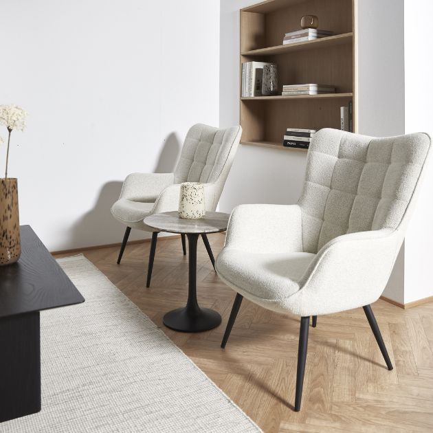 2 vita fåtöljer stående på trägolv framför en vit matta med en inbyggd hylla bakom på väggen