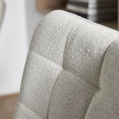 Närbild på vit fåtölj med stoppad klädsel