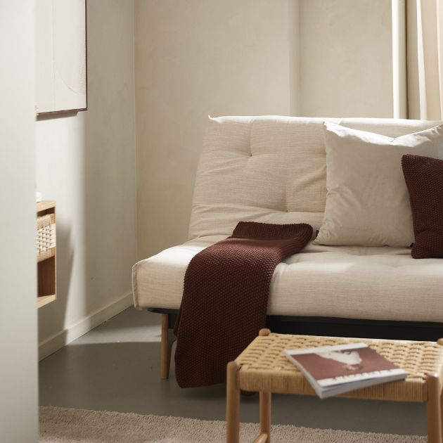 Futon bäddsoffa med röd pläd liggande ovanpå