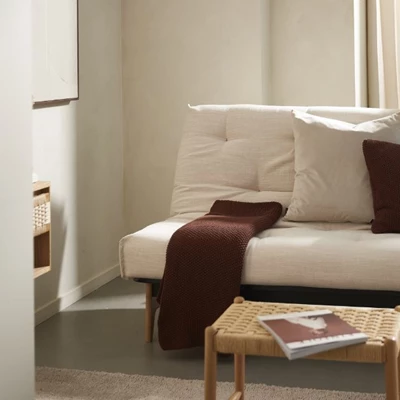 Futon bäddsoffa med röd pläd liggande ovanpå