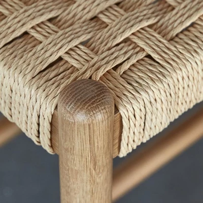 Närbild på bänk med flätad fransk sits och ben i ek