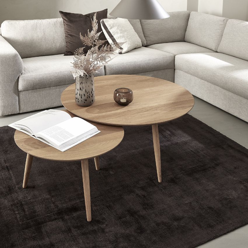 2 soffbord i trä i olika storlekar, satta ihop som sidobord på mörk matta. Bordarna står bredvid en grå hörnsoffa