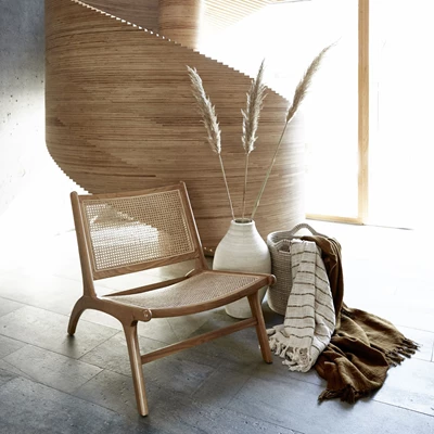 Fåtölj i rotting med vaser framför trappskulptur