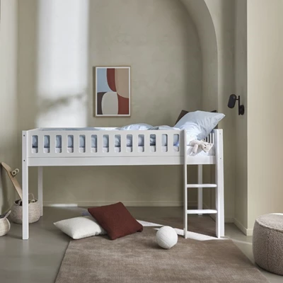 Hög säng i barnrum med kuddar och leksaker