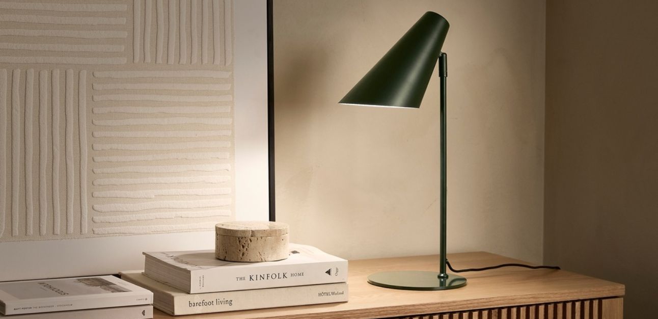Grön skrivbordslampa lyser över böcker och dekoration
