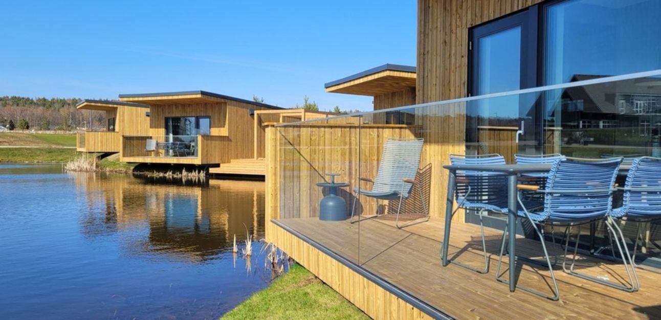 Trähytter vid sjö med terrass och utemöbler