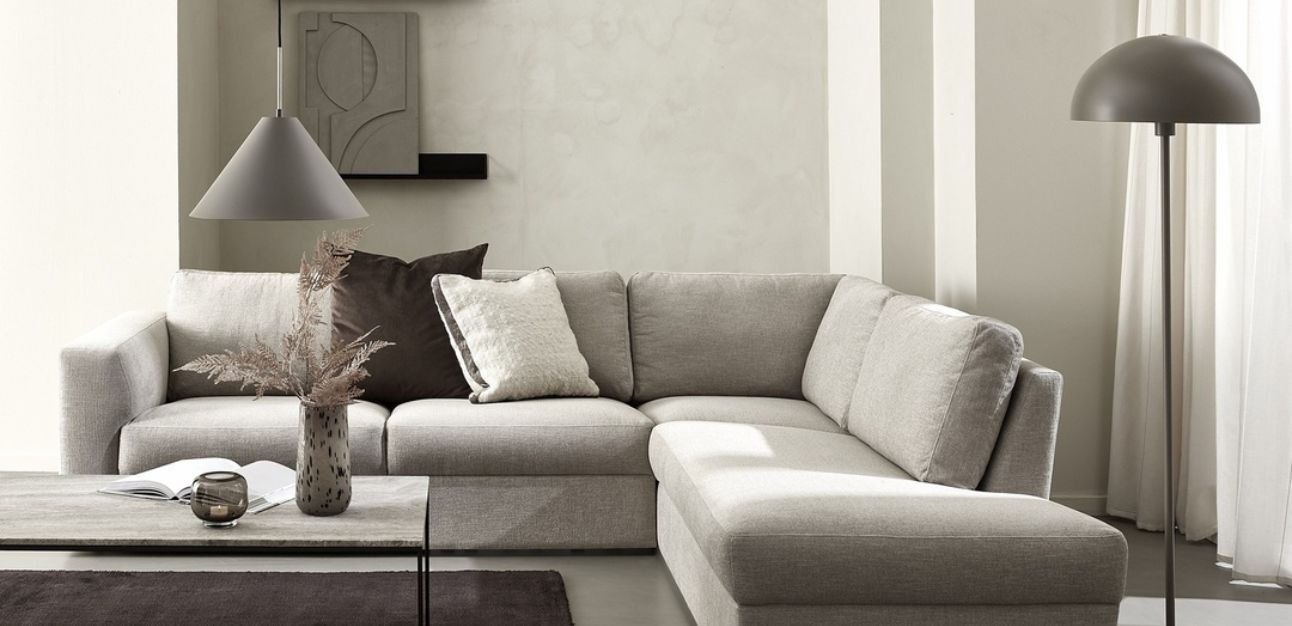 Ljus hörnsoffa med kuddar i stilrent vardagsrum