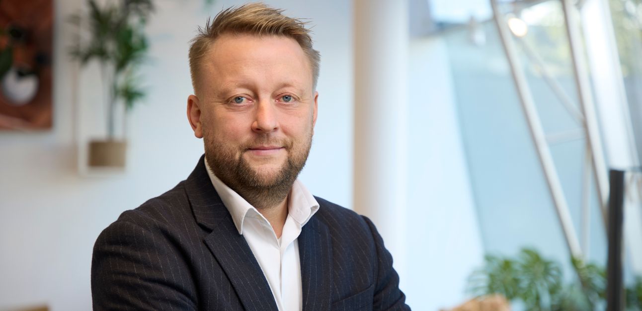 CEO Kim Møller Mønster framför kontorsmiljö med växter