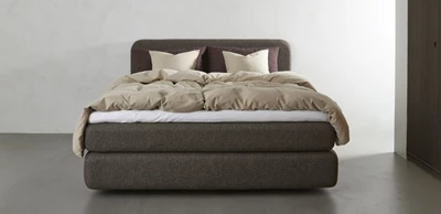 Kontinentalsäng i brunt med bäddat sänglinne i beige