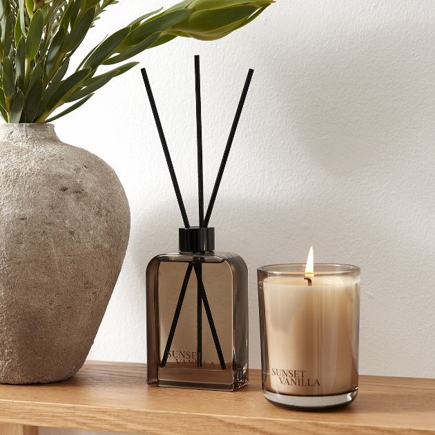 Doftspridare och tänt ljus på trähylla